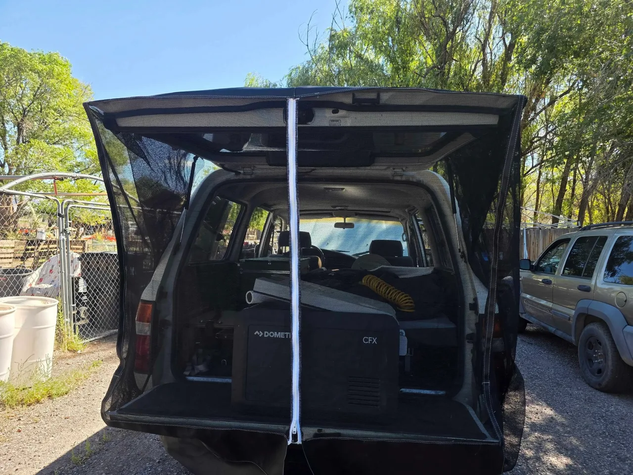 Custom bug net with magnetic side closures, installed across the back of a Land Rover